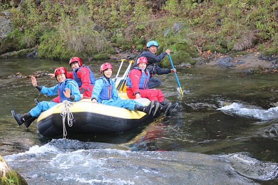 秋の北海道でラフティングを楽しむ参加者たちが川を下る様子。初心者でも安心のガイド付きツアー。