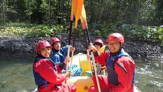 北海道のラフティングツアーでボートに乗る笑顔の参加者たち。仲間と一緒に楽しむアウトドア体験。